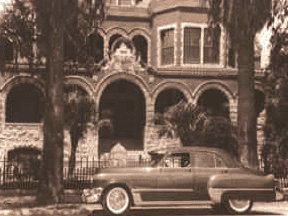 Sepia photo of a car in front of a house